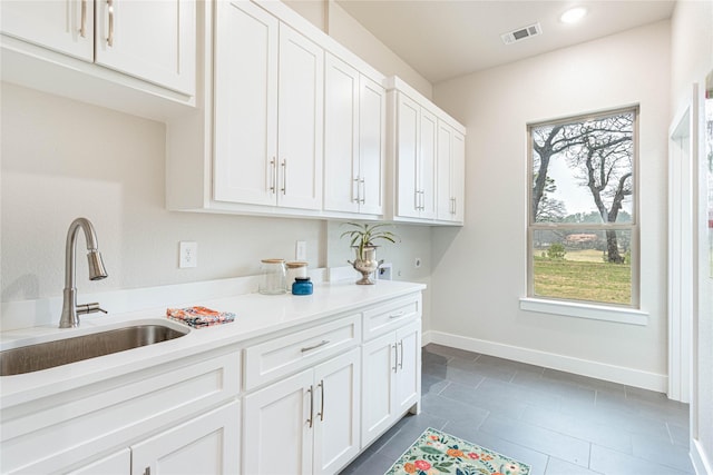 kitchen featuring sink, dark tile patterned floors, and white cabinets