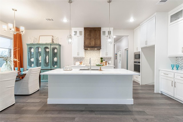 kitchen featuring stainless steel appliances, white cabinetry, and a kitchen island with sink