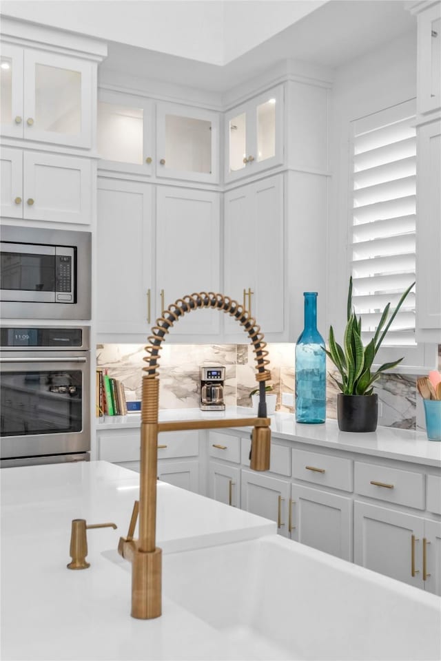 kitchen with appliances with stainless steel finishes, white cabinets, and backsplash