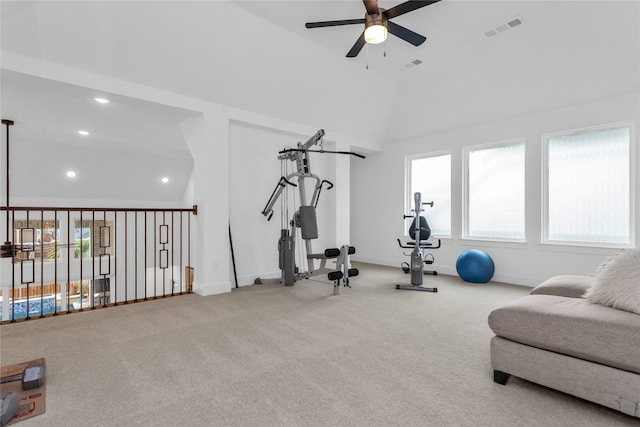 exercise area featuring ceiling fan, light carpet, vaulted ceiling, and plenty of natural light