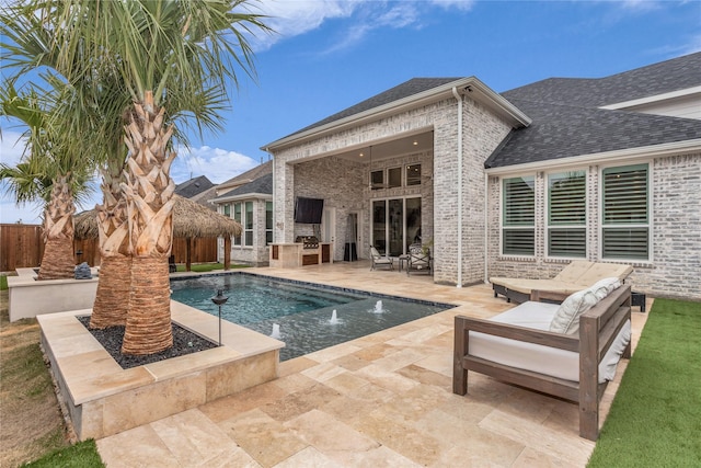 view of swimming pool with a patio, an outdoor kitchen, and pool water feature