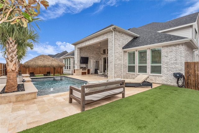 view of swimming pool featuring a lawn, exterior kitchen, pool water feature, a patio area, and a gazebo