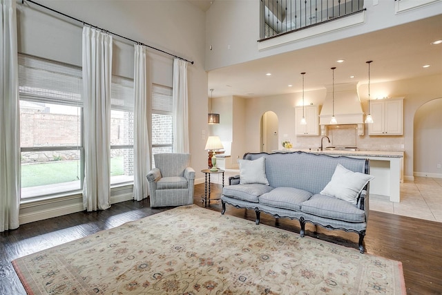 living room featuring dark wood-type flooring, sink, and a towering ceiling