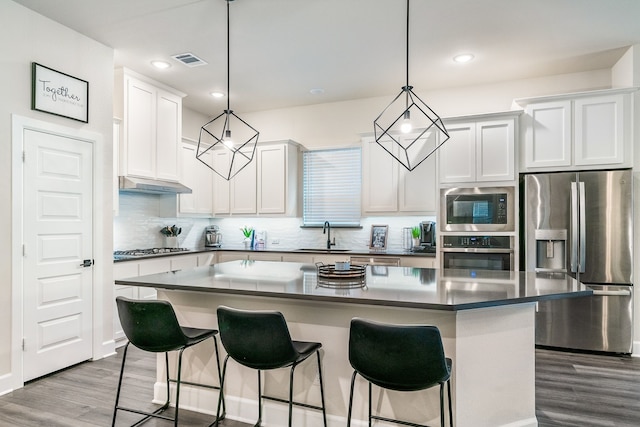 kitchen with white cabinetry, stainless steel appliances, a kitchen island, and hanging light fixtures