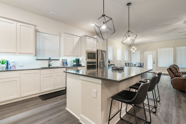 kitchen featuring sink, white cabinetry, hanging light fixtures, stainless steel appliances, and a kitchen island