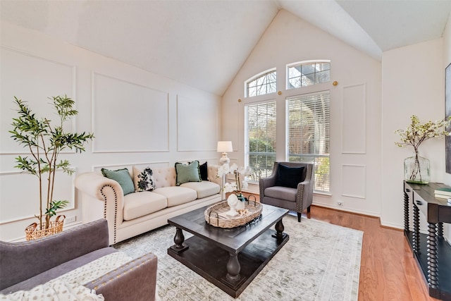 living room featuring high vaulted ceiling and light wood-type flooring