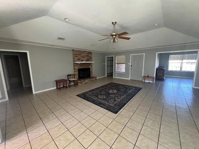 unfurnished living room with light tile patterned floors, vaulted ceiling, a brick fireplace, and ceiling fan