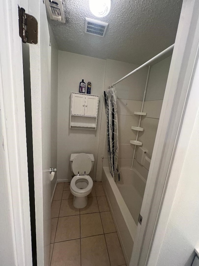 bathroom featuring toilet, tile patterned flooring, and a textured ceiling