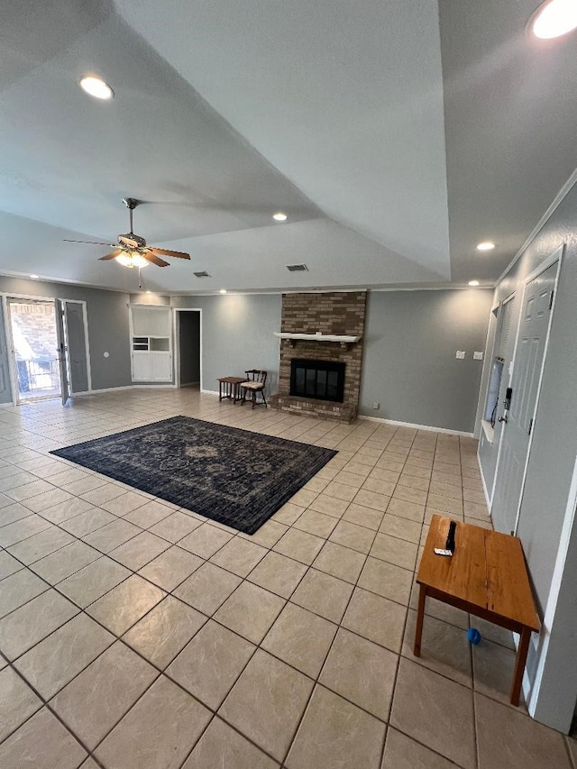 living room with ceiling fan, a brick fireplace, and light tile patterned floors