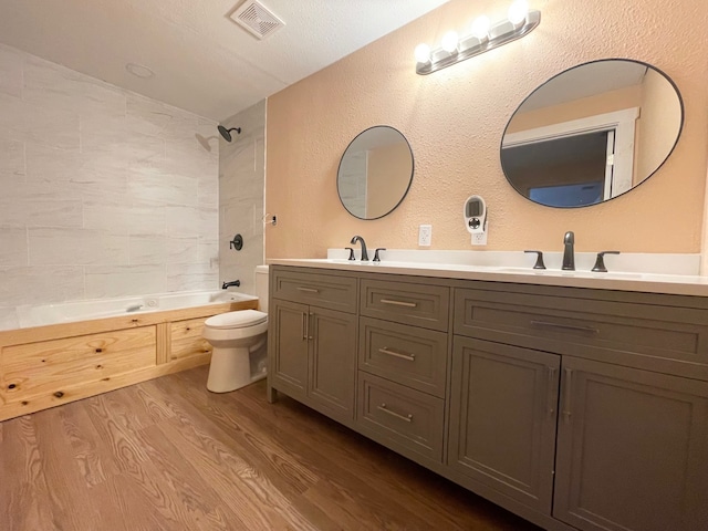 full bathroom featuring visible vents, toilet, a sink, wood finished floors, and shower / bathtub combination