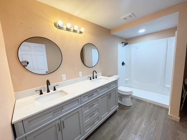 bathroom featuring a shower, hardwood / wood-style floors, vanity, and toilet