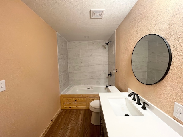 full bath with visible vents, toilet, wood finished floors, a textured wall, and a textured ceiling