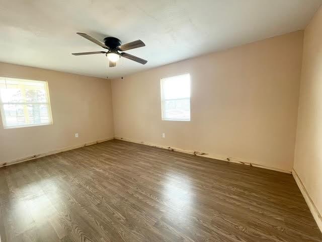 empty room featuring ceiling fan, a healthy amount of sunlight, and wood finished floors