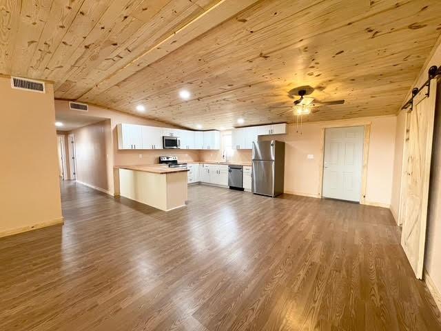 kitchen featuring visible vents, a barn door, appliances with stainless steel finishes, wood ceiling, and dark wood-style flooring