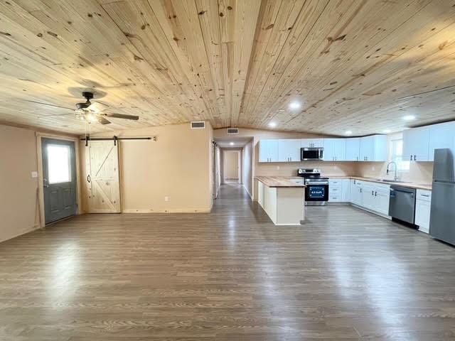 kitchen with wood ceiling, white cabinetry, hardwood / wood-style floors, stainless steel appliances, and a barn door