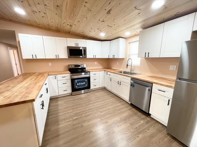 kitchen featuring appliances with stainless steel finishes, butcher block counters, sink, and white cabinets