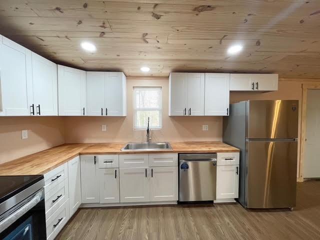 kitchen with white cabinetry, appliances with stainless steel finishes, sink, and wooden counters