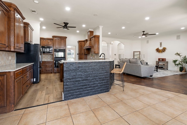 kitchen featuring light tile patterned floors, ornamental molding, black appliances, and a kitchen bar