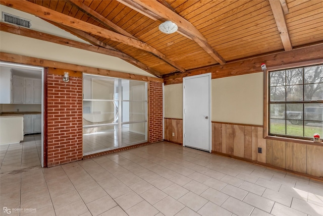 unfurnished room with wood walls, lofted ceiling with beams, light tile patterned floors, wooden ceiling, and brick wall