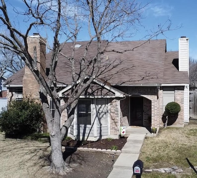 view of front of home with a chimney, a front lawn, and brick siding