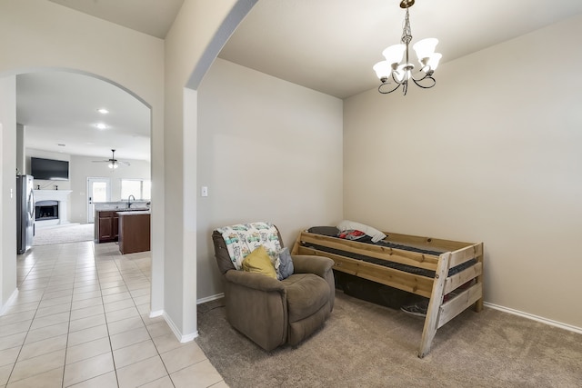 sitting room featuring light tile patterned flooring, ceiling fan with notable chandelier, and sink