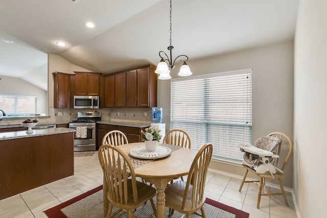 dining space with lofted ceiling, a chandelier, sink, and light tile patterned floors