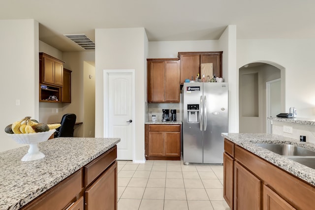 kitchen featuring tasteful backsplash, light tile patterned floors, light stone counters, and stainless steel fridge with ice dispenser