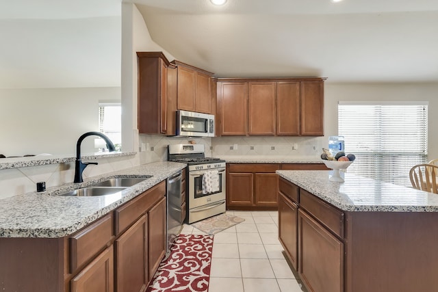 kitchen featuring sink, backsplash, stainless steel appliances, light stone countertops, and light tile patterned flooring