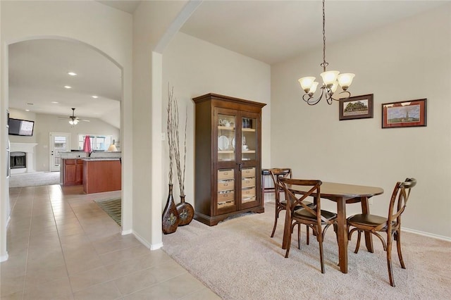 tiled dining space with ceiling fan with notable chandelier