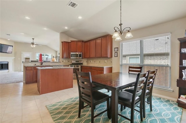 tiled dining space with sink, ceiling fan with notable chandelier, and vaulted ceiling