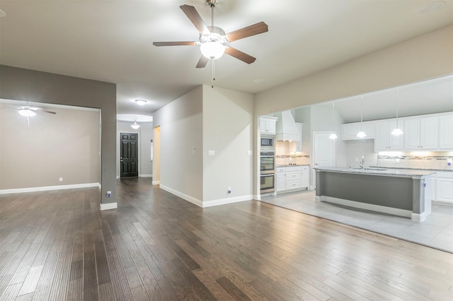 unfurnished living room with sink, hardwood / wood-style flooring, and ceiling fan