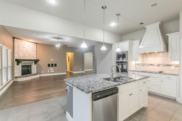 kitchen with appliances with stainless steel finishes, a center island with sink, white cabinetry, sink, and custom exhaust hood