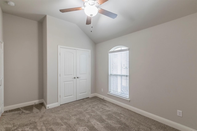 unfurnished bedroom with ceiling fan, vaulted ceiling, light carpet, and a closet