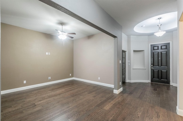 entrance foyer featuring ceiling fan, a tray ceiling, and dark hardwood / wood-style flooring