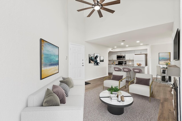 living area with baseboards, wood finished floors, a ceiling fan, and recessed lighting