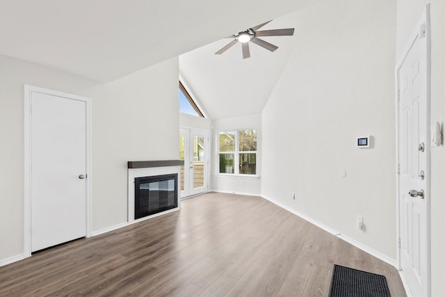 unfurnished living room featuring ceiling fan, baseboards, wood finished floors, and a glass covered fireplace