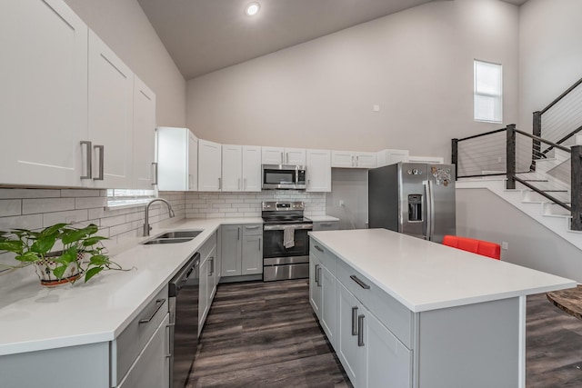 kitchen with stainless steel appliances, a kitchen island, sink, and dark hardwood / wood-style flooring