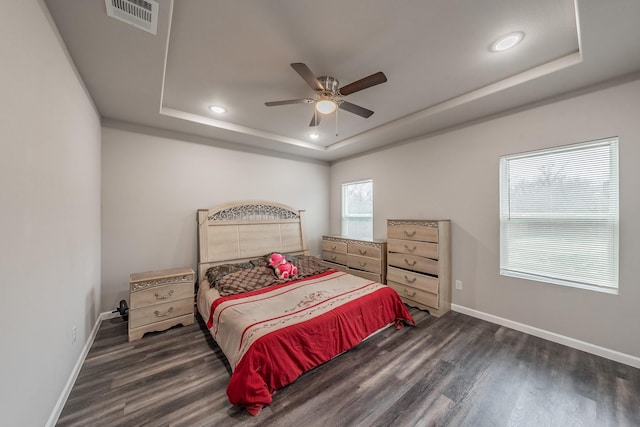 bedroom featuring ceiling fan, dark hardwood / wood-style floors, and a raised ceiling