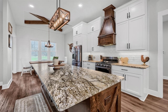 kitchen featuring stainless steel appliances, hanging light fixtures, a center island, and white cabinets