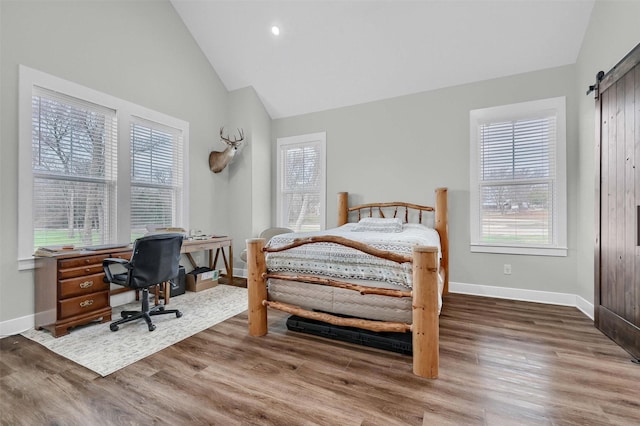 bedroom featuring wood-type flooring, a barn door, and multiple windows