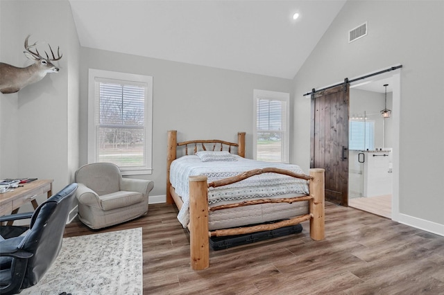 bedroom featuring wood-type flooring, a barn door, and high vaulted ceiling