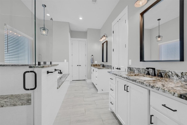 bathroom featuring a healthy amount of sunlight, independent shower and bath, and vanity