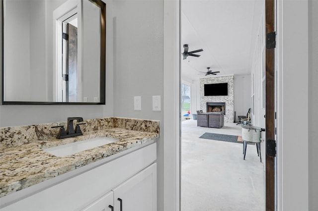 bathroom featuring vanity, a stone fireplace, and ceiling fan