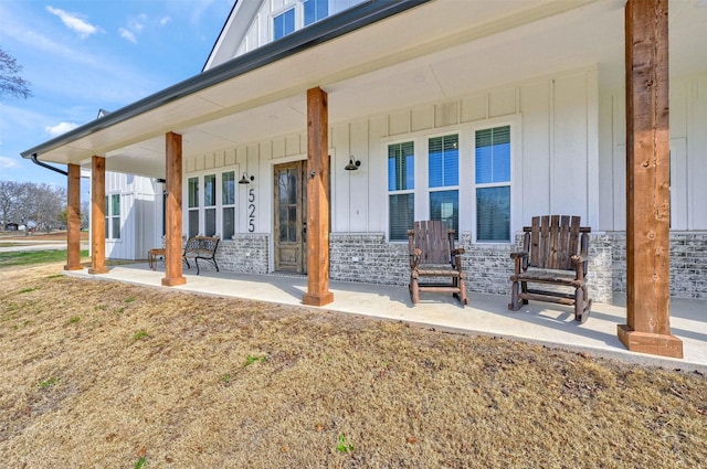 view of exterior entry featuring covered porch and a lawn