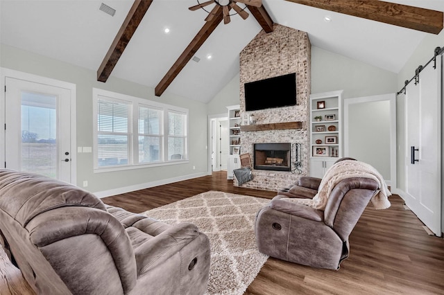 living room featuring ceiling fan, a barn door, hardwood / wood-style floors, and a fireplace