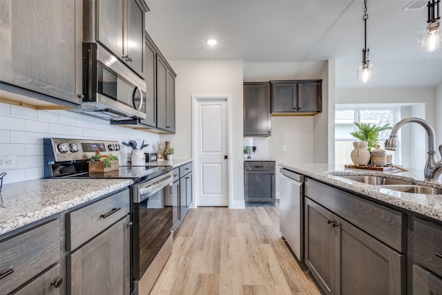 102 Walnut St, Whitesboro, TX 76273 - kitchen with appliances with stainless steel finishes, a sink, light wood-style flooring, light stone counters, and tasteful backsplash