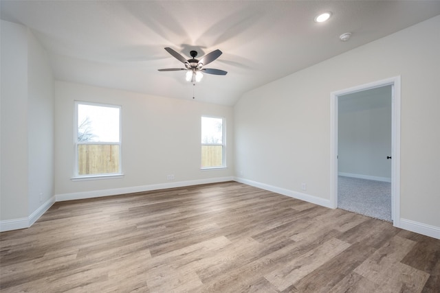 empty room featuring lofted ceiling, wood finished floors, ceiling fan, and plenty of natural light