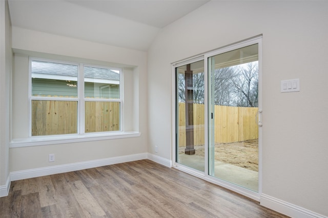 unfurnished room featuring vaulted ceiling, baseboards, and wood finished floors