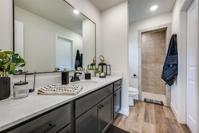 bathroom featuring vanity, toilet, hardwood / wood-style floors, and a tile shower