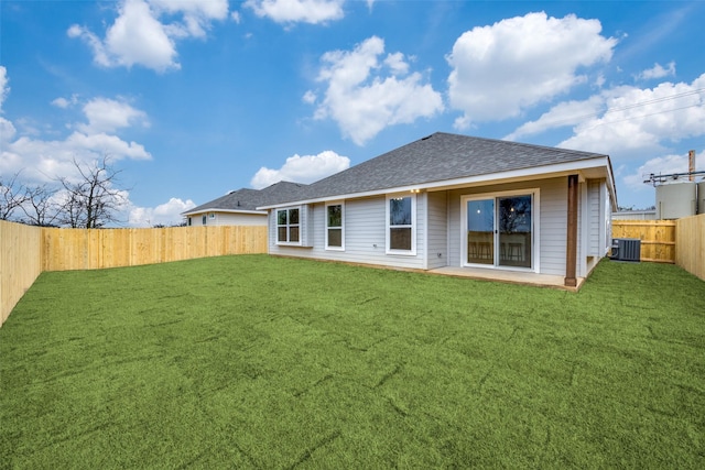 rear view of house featuring central air condition unit and a lawn